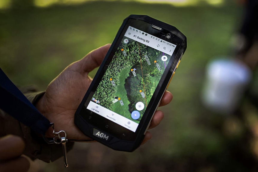 A hand holding a smartphone, which has a map on it.