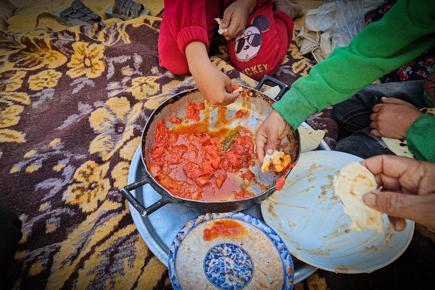 Children scoop out cooked tomatoes with flatbread