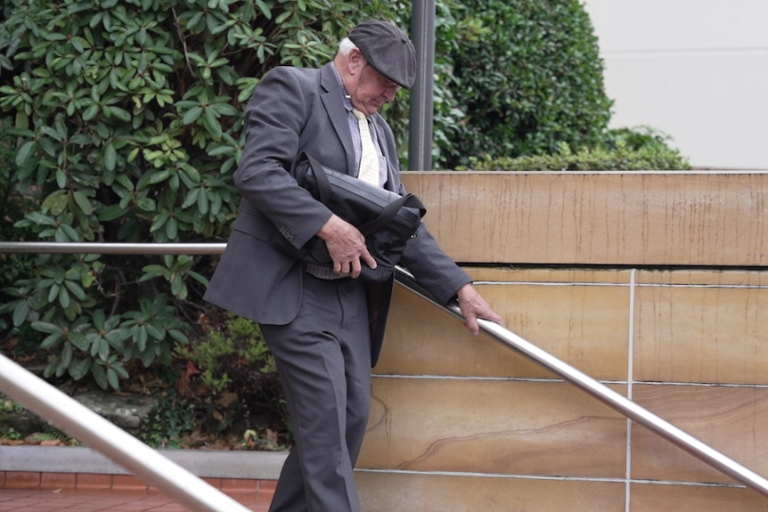 一个戴帽子的男人扶着栏杆走下楼梯