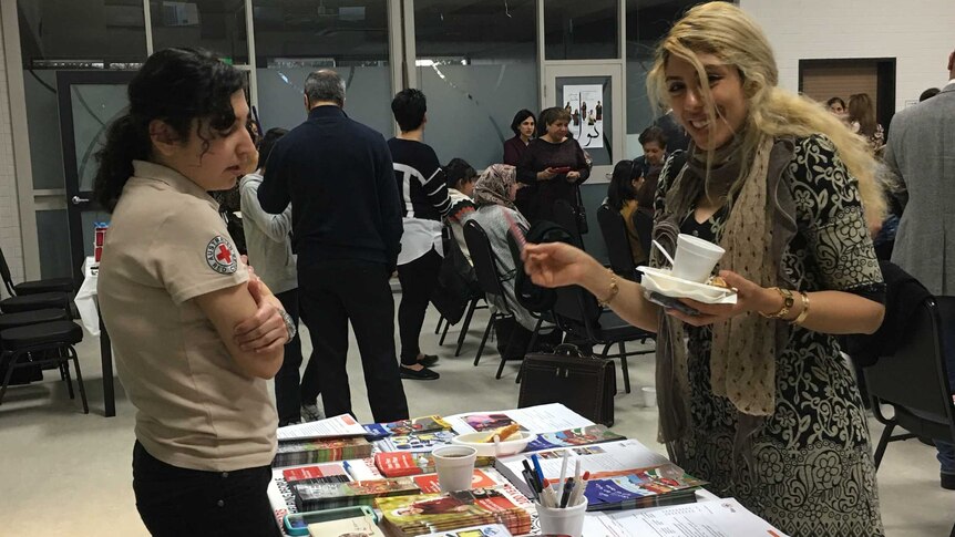 A Red Cross CALD volunteer talks to a woman at a community health forum.