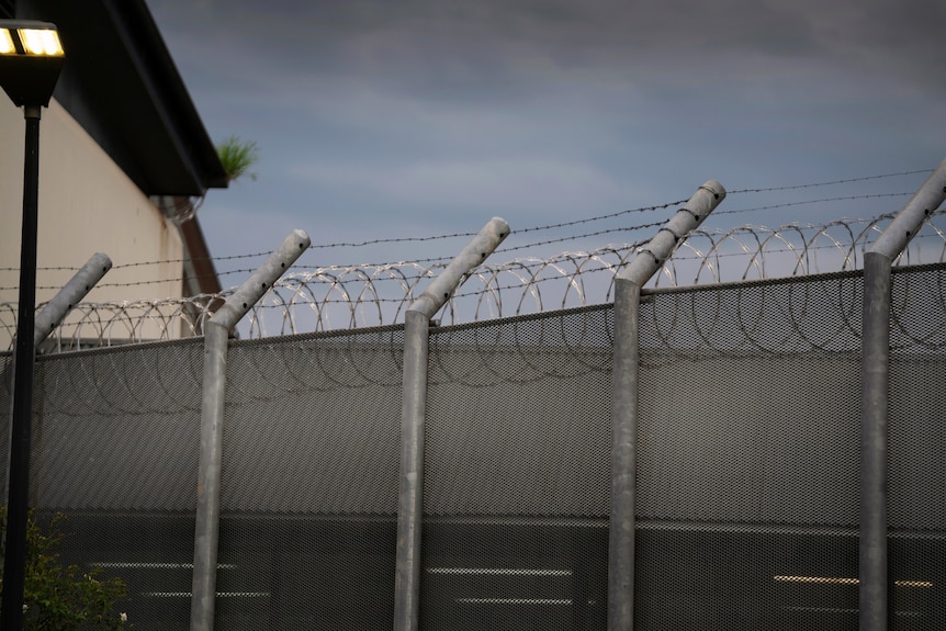 A shot of the exterior gate outside a detention centre with barbed wire.
