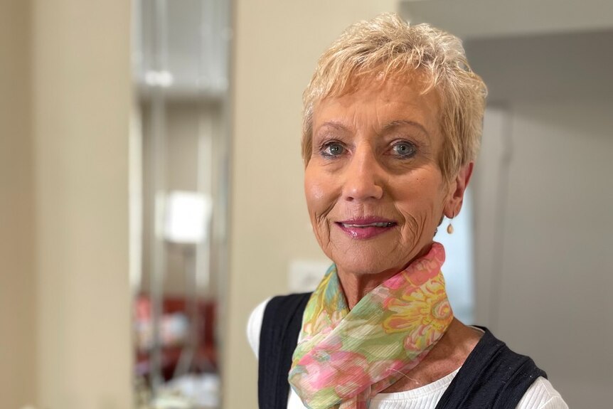 A middle aged woman stands in a light coloured room