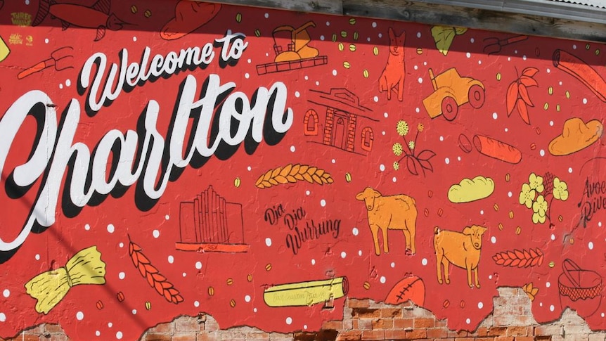 Photo of a mural, the wall is pained red with welcome in Charlton in white 