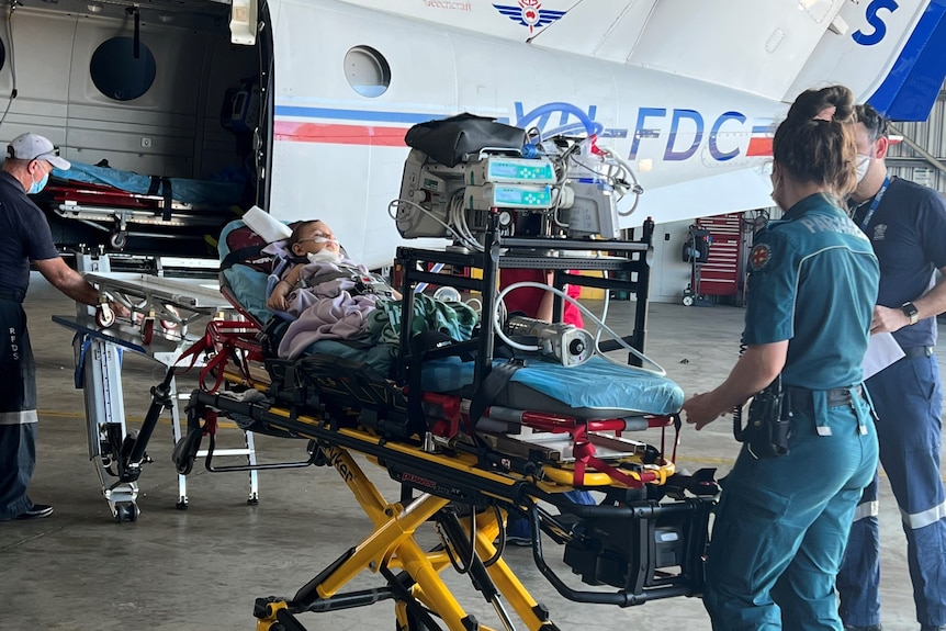 Conall Westcott is on a stretcher being wheeled into an RFDS plane. 