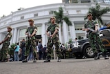 Armed government troops stand guard outside the bomb-damaged Ritz-Carlton hotel in Jakarta