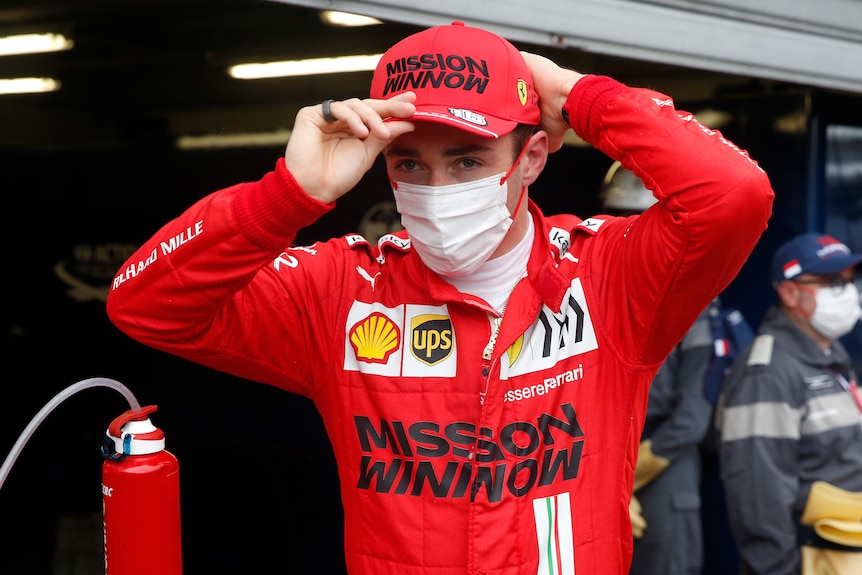 Ferrari driver puts on his cap in the pitlane.