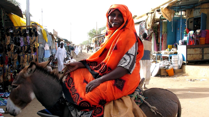 Woman sitting on donkey in market in Sudan