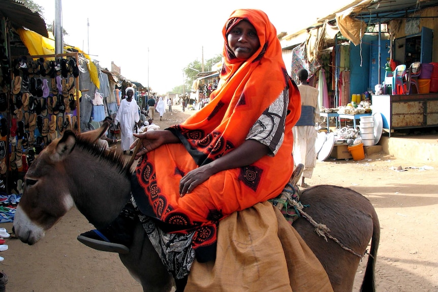 Woman sitting on donkey in market in Sudan