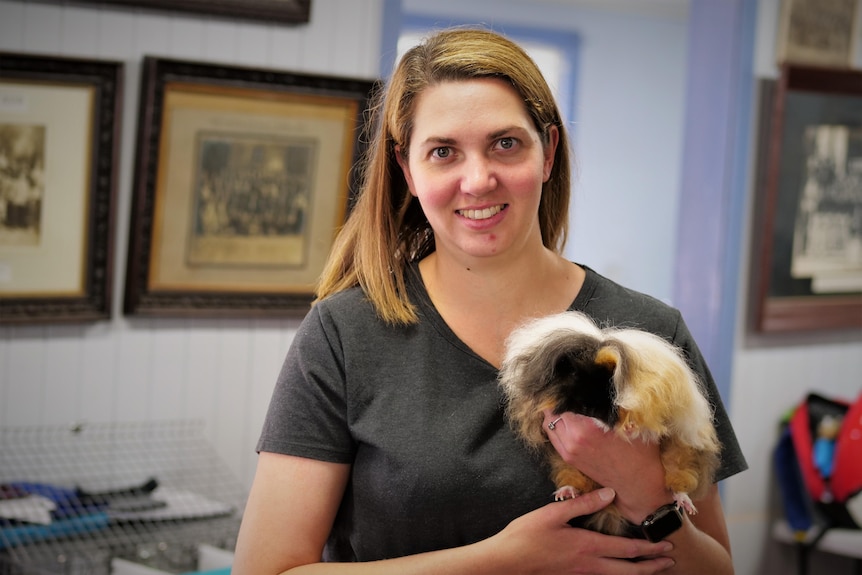 A woman holding a long haired guinea pig