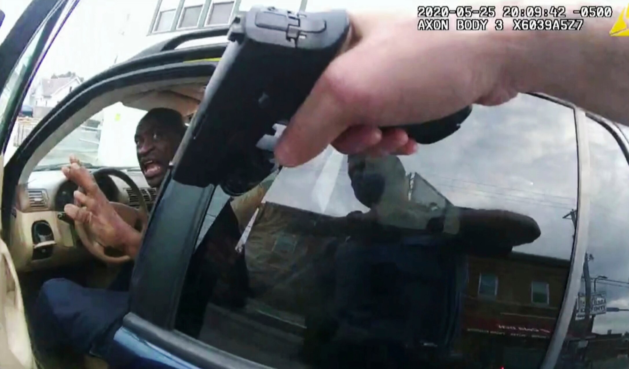 George Floyd reacts as a police officer points a gun at him.