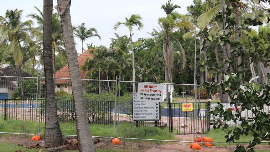 resort buildings, empty swimming pool behind fence and no entry sign