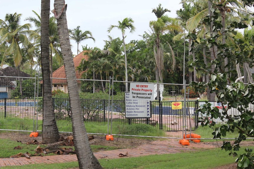 resort buildings, empty swimming pool behind fence and no entry sign