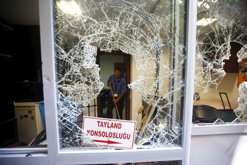 A man removes broken glass from a window of Thai honorary consulate in Istanbul