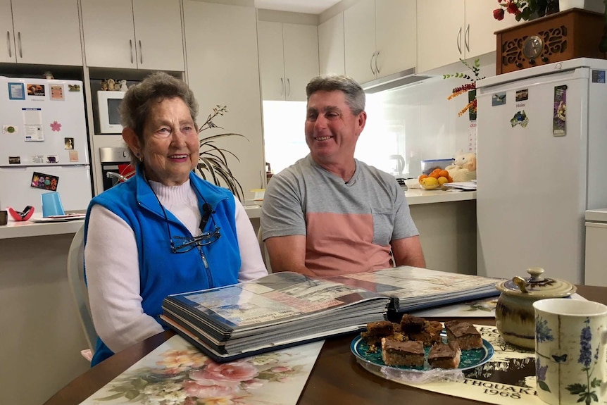 A lady and her son look at a photo album.