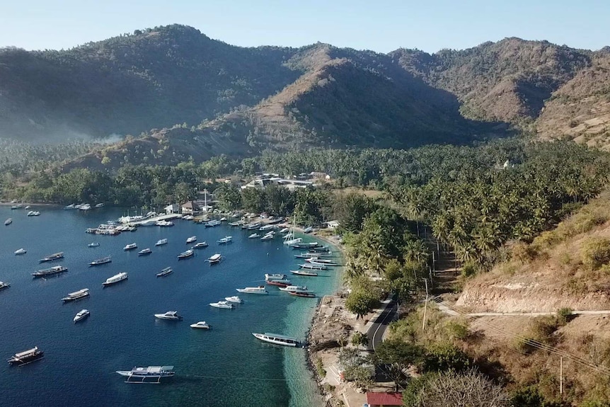 Boat are anchored in a bright blue bay overlooked by mountains