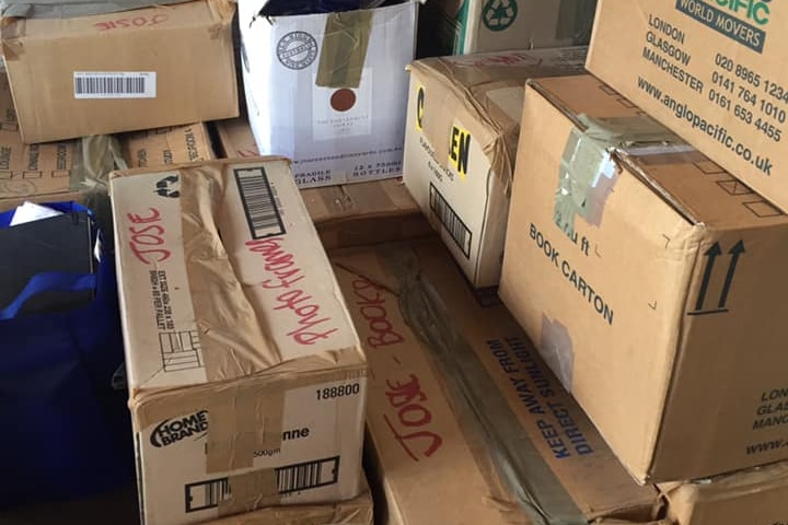 A large pile of taped up cardboard boxes, labelled with the name Josie, stacked in a room or garage space.