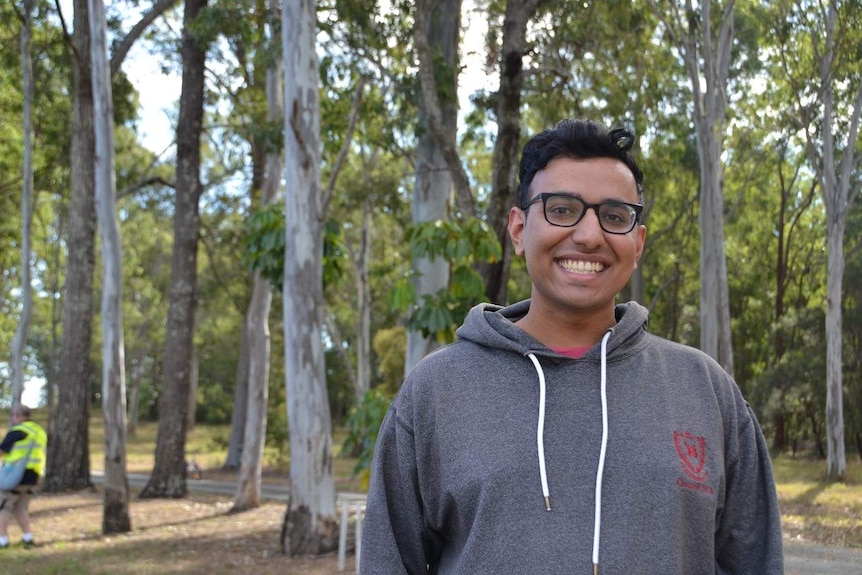 Arush Saraswat smiles under gum trees wearing glasses.