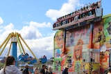 Spectators walk past carnival rides at an agricultural show