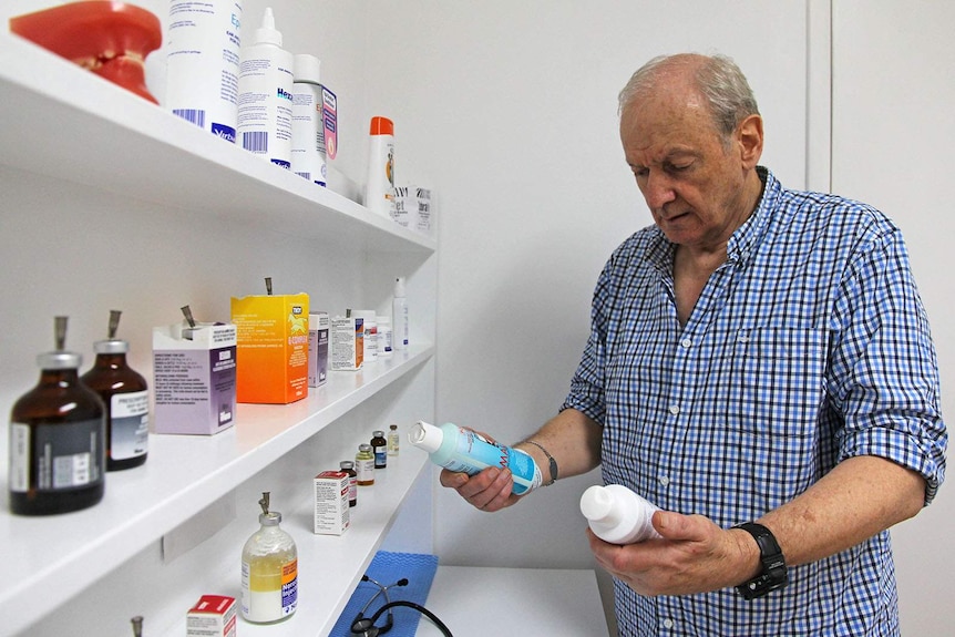 Veterinarian Dr John Chambers examines two bottles of shampoo in his office.