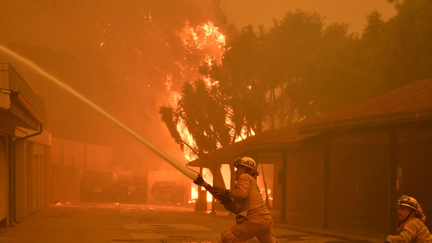 Firefighters hose down a condo unit during the Woolsey Fire in Malibu.