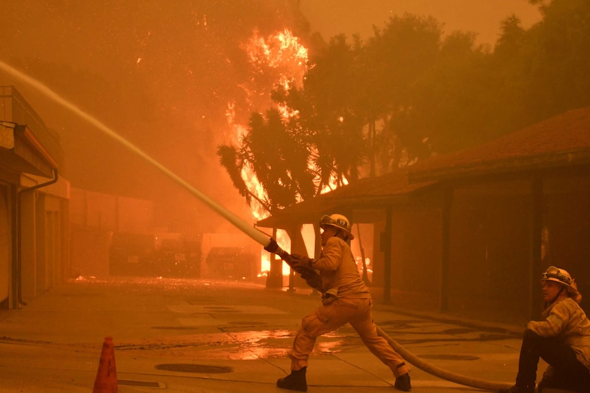 Firefighters hose down a condo unit during the Woolsey Fire in Malibu.