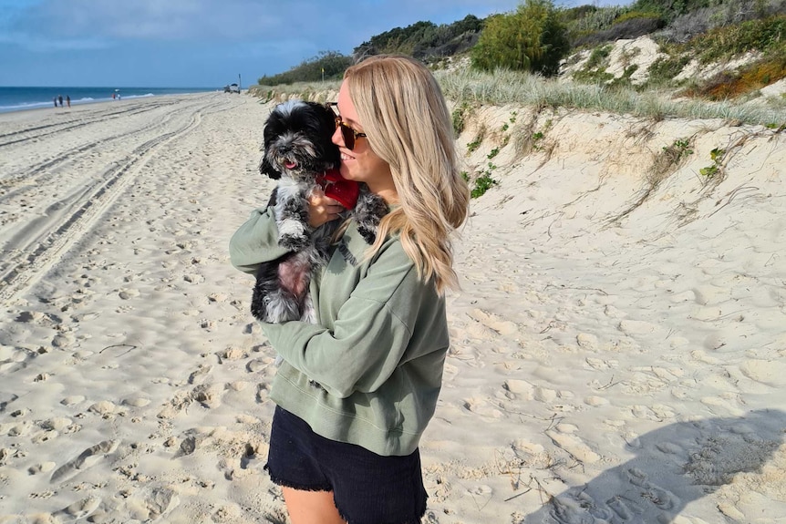 Kellie Scott holding dog Peppa on the beach