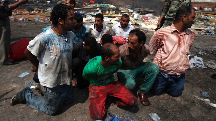 Suspects are rounded up near a burnt-out building next to the Rabaa Adawiya mosque in Cairo