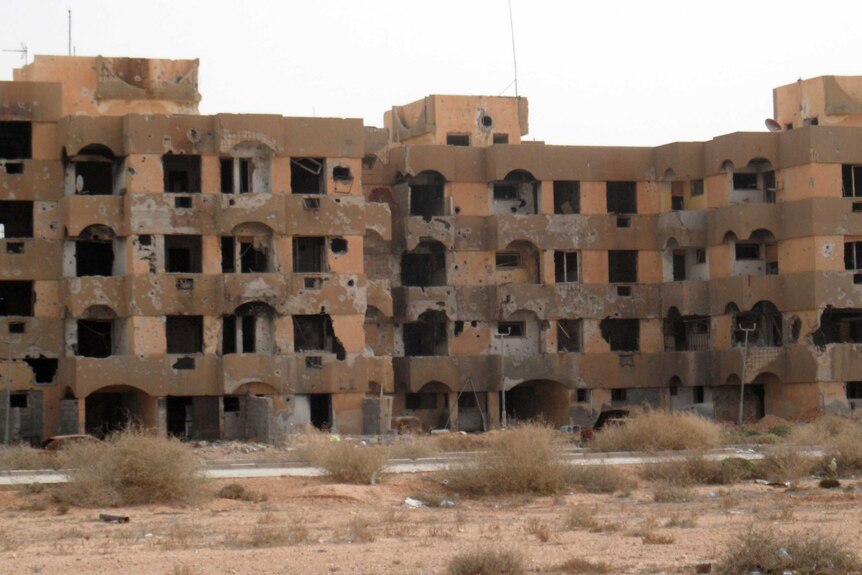 A once-inhabitated apartment block, ridden with bullet holes, stands abandoned in the Libyan town of Tawergha