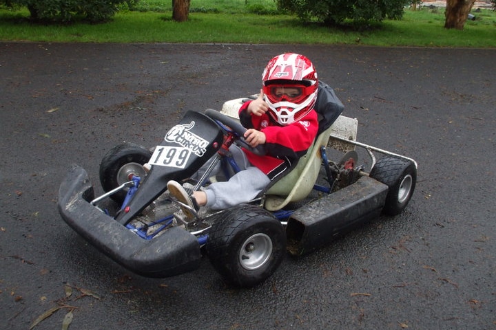 A young boy wearing helmet in go-cart