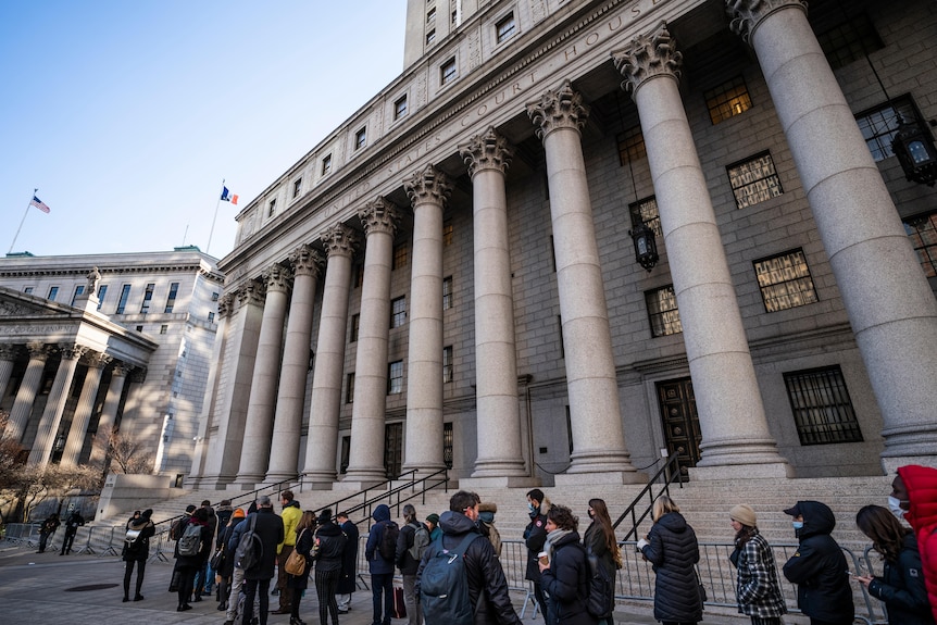 A line of people wait to enter the courthouse.