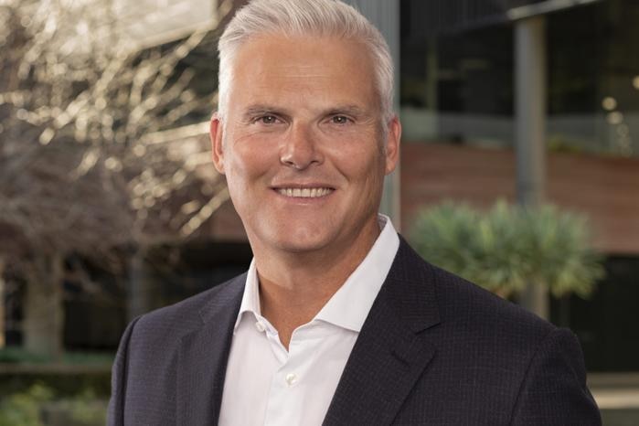 A man wearing a suit smiles at the camera