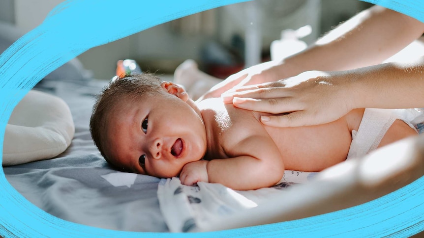 Baby lying on tummy on a bed, with two hands giving the baby a massage for a story about how to deal with visitors after birth