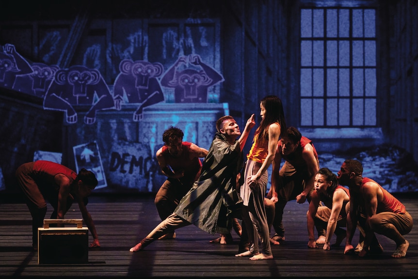A group of dancers perform onstage with illustrated images of monkeys projected, graffitti-style on the backdrop.