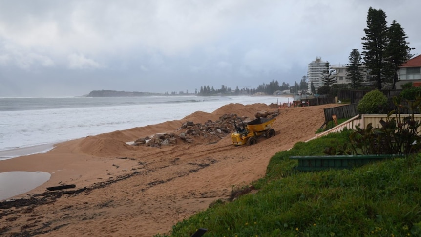 A gloomy skyline over Collaroy Beach with a small tractor in shot