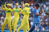 Indian captain Virat Kohli walks off the SCG as Australian cricketers celebrate.