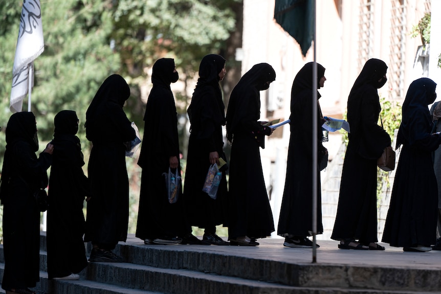 穿着黑色长袍、头巾的阿富汗女学生排队。