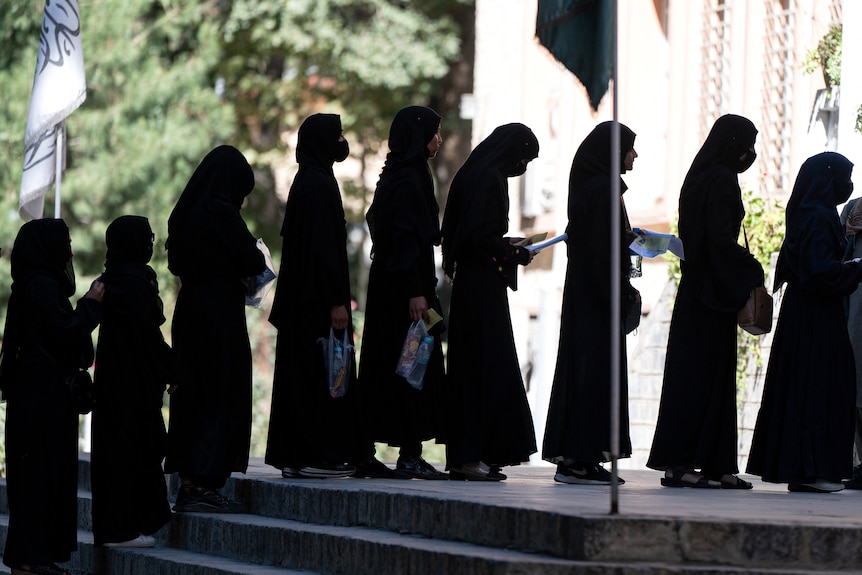 Le studentesse afghane si mettono in fila con abaya neri e foulard.
