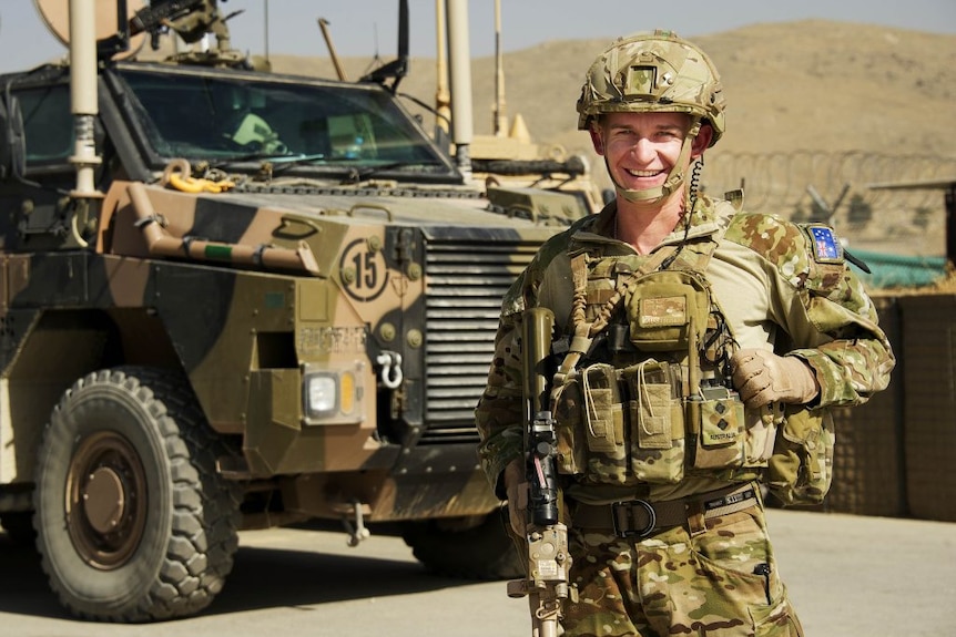 A defence force serviceman in uniform by a military grade vehicle