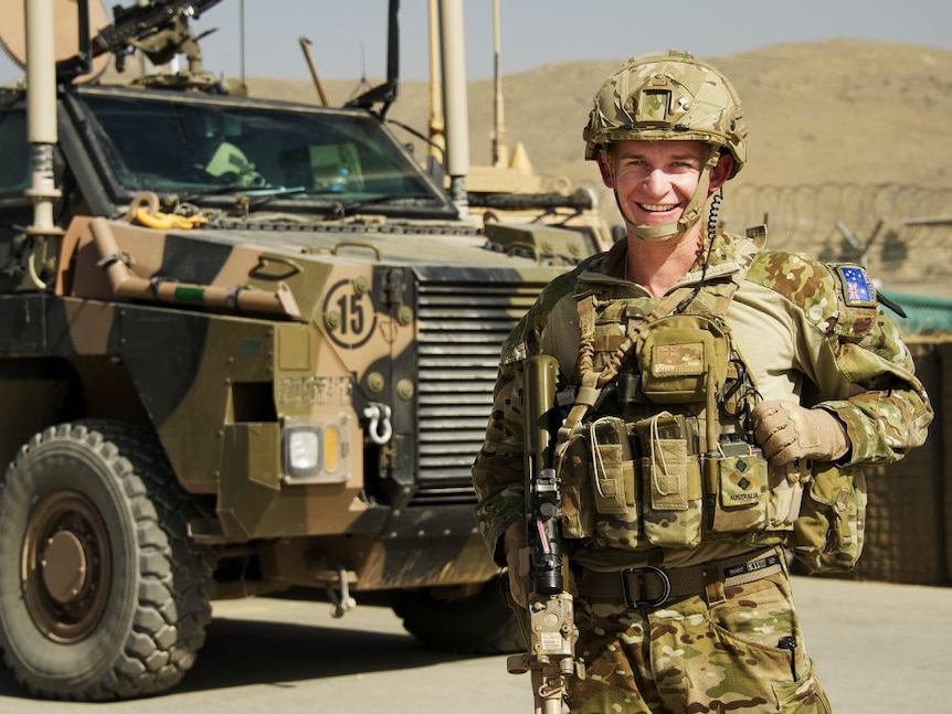 A defence force serviceman in uniform by a military grade vehicle