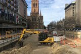 An excavator starts digging in Melbourne's City Square in the shadow of St Paul's Cathedral.