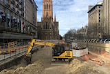 An excavator starts digging in Melbourne's City Square in the shadow of St Paul's Cathedral.