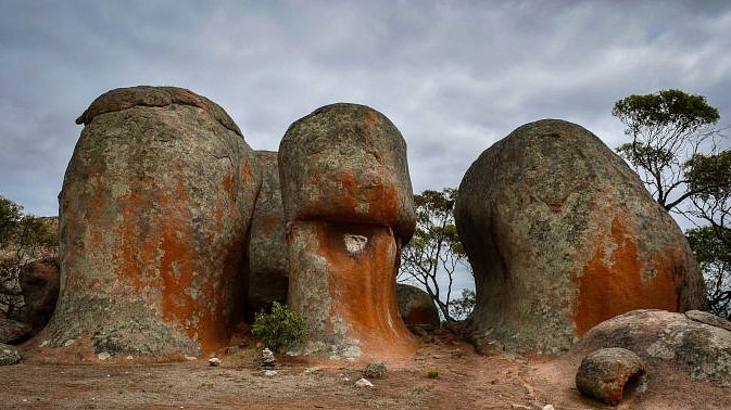 Three rocks formations stick out of the ground, there is a path leading between two of them.