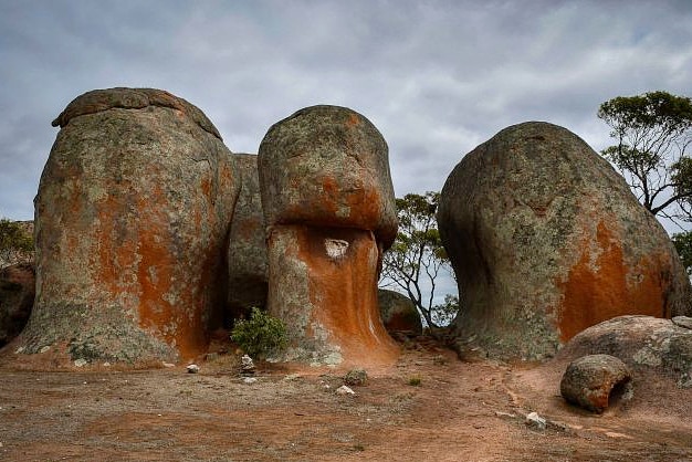 Three rocks formations stick out of the ground, there is a path leading between two of them.