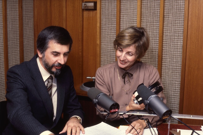 A woman and man with microphones in front of them. 