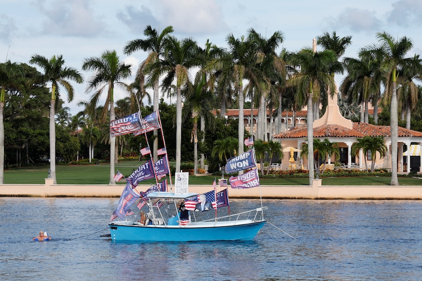 A boat adorned with Trump flags floats past his Mar-a-Lago resort