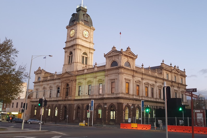 Old historic town hall building with traffic lights and cars in the foreground