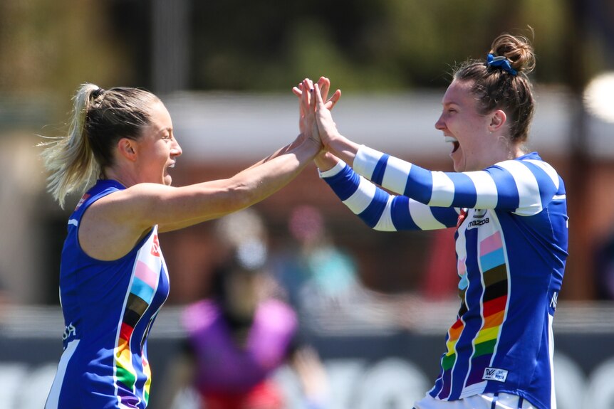 Two North Melbourne AFLW players celebrate a goal.