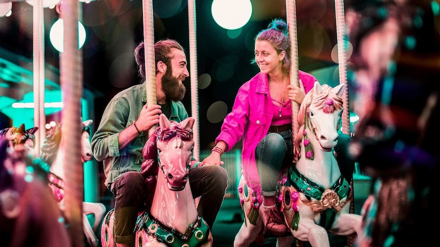 Man and woman ride carousel together holding hands for a story about not feeling like sex in a long-term relationship.