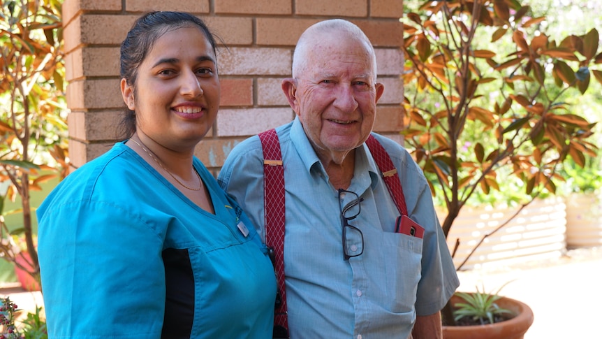 A nepalese woman in aged care uniform next to an elderly man