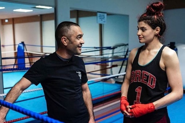 Mahyar Monshipour and Sadaf Khadem stand talking inside a boxing ring